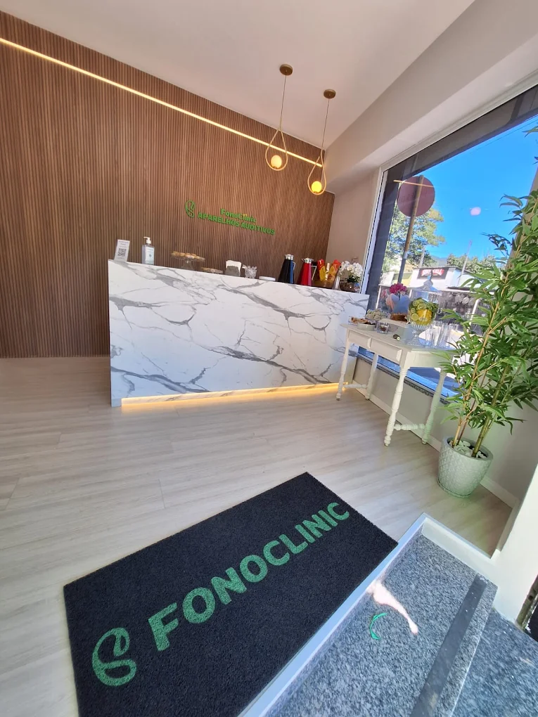 Interior da FonoClinic em Itajubá: recepção moderna com bancada de mármore e ambiente acolhedor